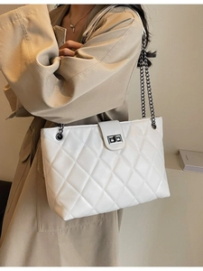 Sac fourre-tout matelassé blanc avec chaîne argentée porté par un mannequin en trench