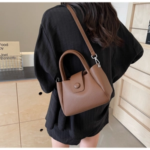 Sac seau en cuir marron grainé porté à l'épaule pour un style moderne décontracté