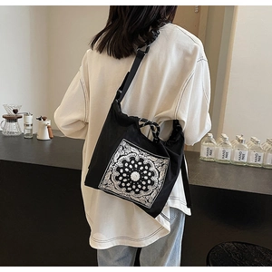 Detail einer schwarzen Canvas-Tasche mit weißem Paisley-Muster und geknotetem Griff