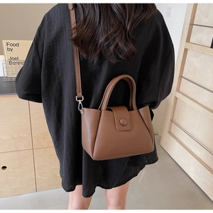 Rear view of a model wearing a brown lychee pattern bucket bag with a top handle and strap