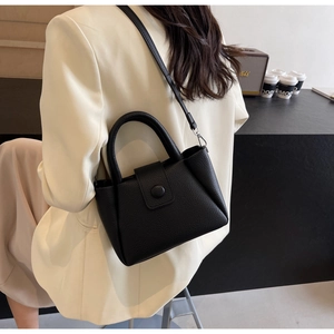 Detail of black lychee grain leather bucket bag with top handle and slender strap