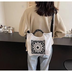 Detail der weißen Canvas-Tasche mit schwarzem Paisley-Muster und Webgriff