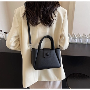 Schicke schwarze Eimer-Tasche aus Leder mit Lychee-Muster zu einem cremefarbenen Blazer