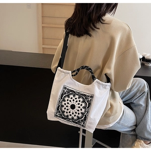 Detail einer weißen Canvas-Tragetasche mit Paisley-Muster und schwarzem Schultergurt