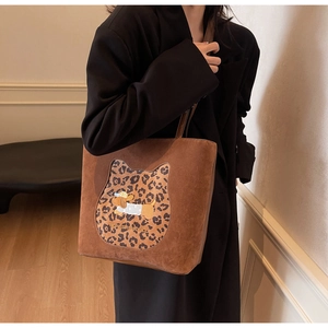 Close-up of brown suede tote bag with leopard cat patch and chic cartoon dog print