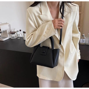 Detail of black lychee grain leather bucket bag with top handle and detachable shoulder strap