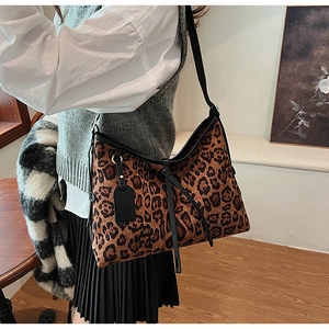 Détail du grand sac hobo léopard avec large bandoulière noire porté par un mannequin
