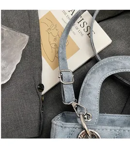 Detail of silver metal lobster clasp and adjustable denim shoulder strap on bag