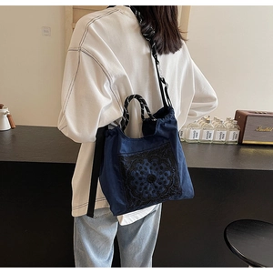 Detail der dunkelblauen Paisley-Stickerei-Tasche mit gewebten Seilgriffen im Café-Stil