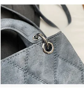 Close-up of quilted grey-blue fabric and polished silver ring hardware on a handbag