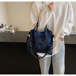 Detailaufnahme der dunkelblauen Canvas-Tasche mit schwarzer Stickerei und gestreiften Seilgriffen