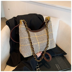 Detail of vintage plaid shoulder bag with metal chain strap on chic neutral background