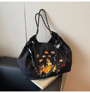Detail der süßen Katzenstickerei auf schwarzem Nylon-Shopper mit Kordelzug