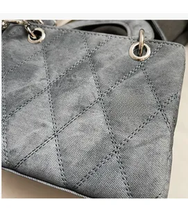 Detail of grey-blue denim quilted handbag featuring classic stitching and silver metal rings