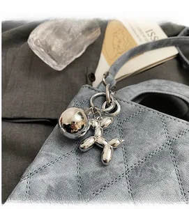 Close-up of a silver mirror balloon dog metal charm on a grey quilted handbag
