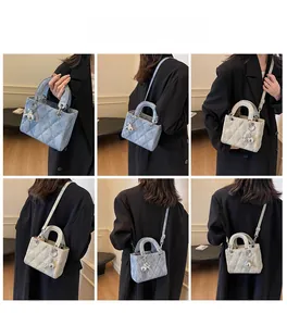 Quilted crossbody bag shown in blue and beige with adjustable straps and silver charms