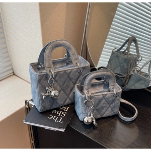 Detail view of denim texture quilted handbags with silver charms and elegant lighting