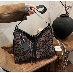 Détail du sac cabas à motif léopard avec lanières en cuir noir et pompon décoratif