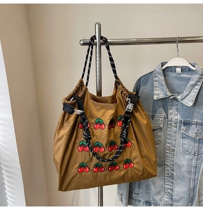 Detail van nylon tas met trekkoord, kersenborduursel en gestreepte touwhandvatten