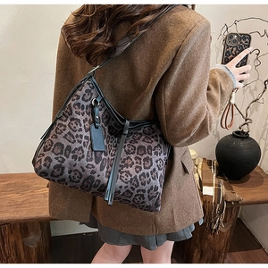 Détail d'un sac cabas léopard vintage avec anses en cuir noir porté par un mannequin