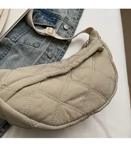 Close-up of beige quilted dumpling bag with soft fabric and adjustable strap