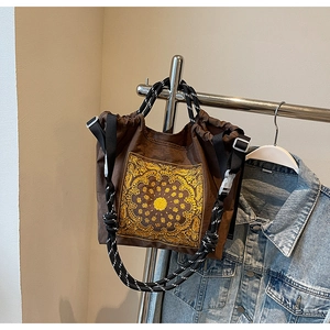 Detail einer braunen Vintage-Tasche mit goldenem Paisley-Muster und Webgriffen am Bügel