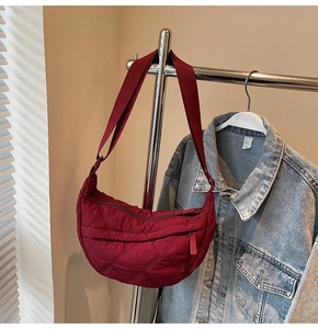 Detail of burgundy quilted crescent bag with adjustable strap and diamond stitching