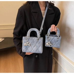 Detail view of quilted grey crossbody bag set with silver balloon dog charms