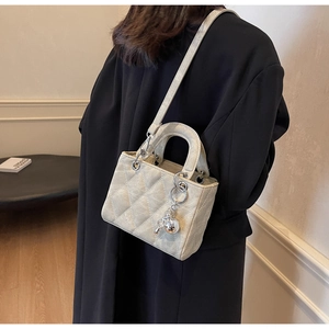 Close-up of beige quilted leather handbag with elegant silver hardware and ball charm