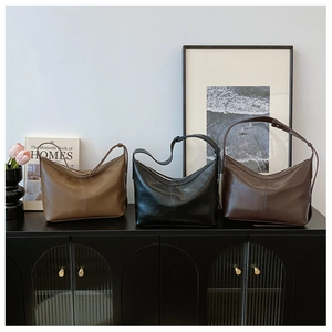 Three elegant hobo bags in brown, black, and coffee displayed on a vintage cabinet