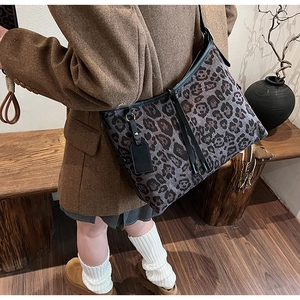Détail du sac cabas léopard avec lanières en cuir noir et cordon de serrage latéral