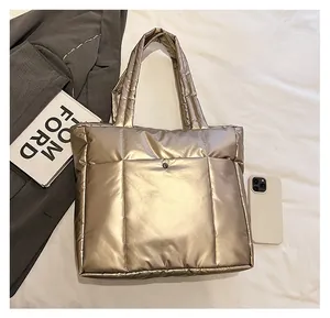Détail d'un sac cabas matelassé doré avec finition métallique et poche avant boutonnée