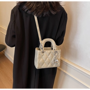 Close-up of champagne quilted handbag featuring classic cannage stitching and metal charms