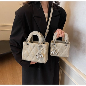 Close-up of beige quilted handbags featuring silver balloon dog charms and straps
