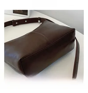 Detail view of coffee brown vintage leather shoulder bag with wide strap and rivet buckle