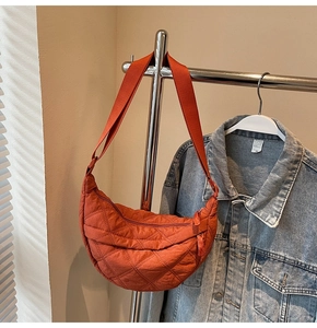 Detail of orange quilted crescent bag with adjustable strap and zip closure
