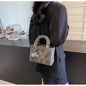 Gray quilted handbag with metallic balloon dog charm on black blazer outfit back view