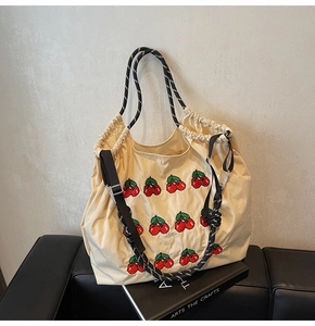 Detail van de gebroken witte canvas shopper met kersenborduursel en geweven handgrepen