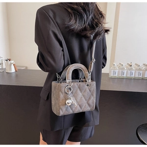 Detailed view of grey quilted handbag with silver hardware and detachable crossbody strap