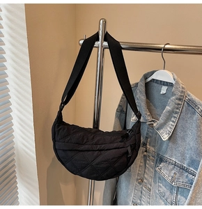 Close-up of black quilted crescent bag with soft padded texture and adjustable strap