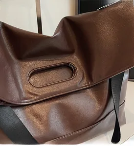 Detailed macro view of dark brown tote bag showing pebbled leather texture and oval handle