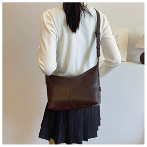 Detail view of a vintage dark brown shoulder bag with adjustable silver buckle strap