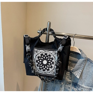 Detail der schwarzen Paisley-Tragetasche mit gewebten Griffen und verstellbarem Schultergurt