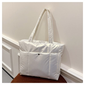 Sac fourre-tout matelassé blanc en nylon avec bouton pression sur un fauteuil doux