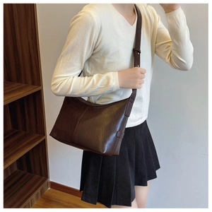 Detailed view of dark brown faux leather shoulder bag with adjustable metal buckle strap