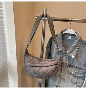 Macro view of a quilted dark grey crescent bag with wide adjustable shoulder strap