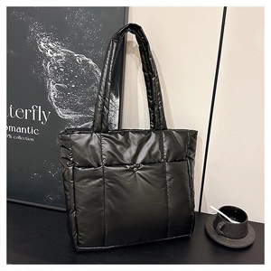 Détail de ce sac fourre-tout noir matelassé avec surpiqûres carrées et poche à pression