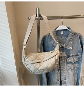 Close-up of beige quilted dumpling bag with rhombic stitching on a metal hanger