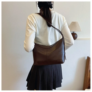 Deep brown faux leather underarm bag shown on shoulder to display drape and size