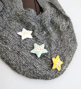 Nahaufnahme der grauen Stricktasche mit bunten Sternanhängern und weichem Stoffdetail